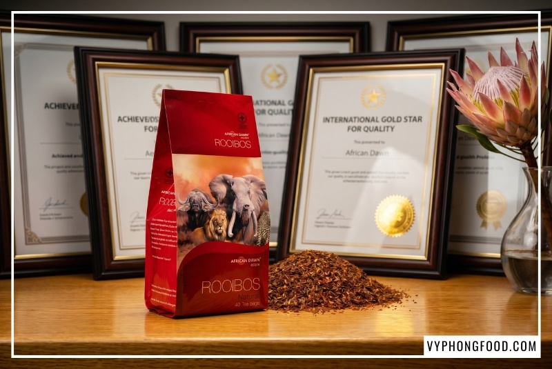 Hình ảnh hộp hồng trà rooibos Nam Phi túi lọc thương hiệu African Dawn nhập khẩu chính ngạch. Bài viết giải đáp thắc mắc trà rooibos mua ở đâu uy tín và hướng dẫn cách phân biệt trà thảo mộc tốt cho sức khỏe chính hãng do Vy Phong Food phân phối độc quyền tại Việt Nam.