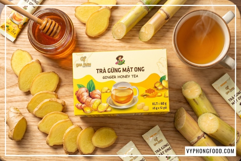 Nguyên liệu gừng sẻ Tiên Phước và mật ong rừng óng ả xung quanh hộp sản phẩm QNA Farm, minh họa cho bài viết về giá 1 hộp trà gừng mật ong hòa tan nguyên chất, cam kết tiêu chuẩn 3 KHÔNG uy tín tại VyPhongFood.