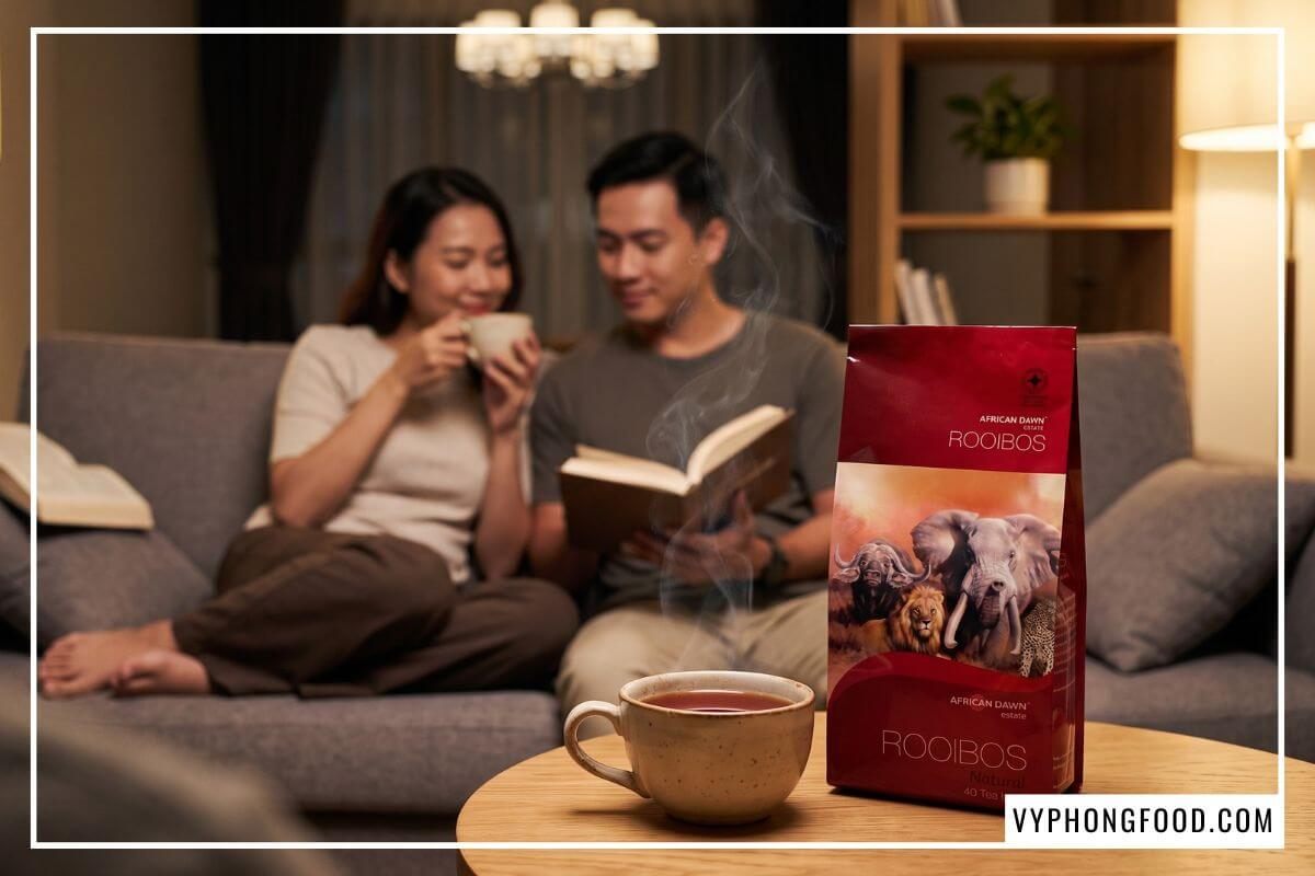 Gói hồng trà rooibos African Dawn cạnh tách trà ấm buổi tối gia đình khẳng định uống trà tốt cho sức khỏe dài lâu