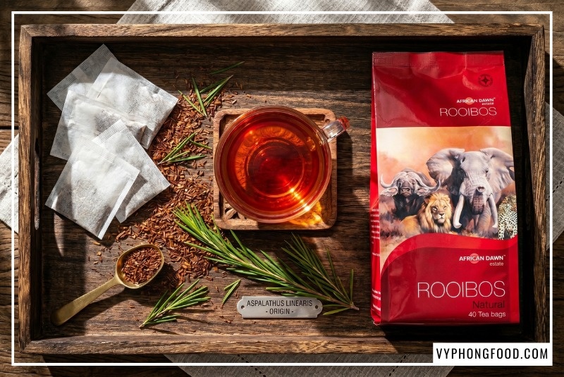 Tách trà rooibos Nam Phi nguyên chất với sắc đỏ nâu hổ phách bắt mắt, tỏa hương gỗ mộc mạc. Đây là thức uống thuộc nhóm trà thảo mộc không caffeine từ lá cây Aspalathus linearis, có tác dụng chống oxy hóa, hỗ trợ tiêu hóa và giúp ngủ ngon. Sản phẩm minh họa thuộc thương hiệu African Dawn cao cấp do Vy Phong Food phân phối.