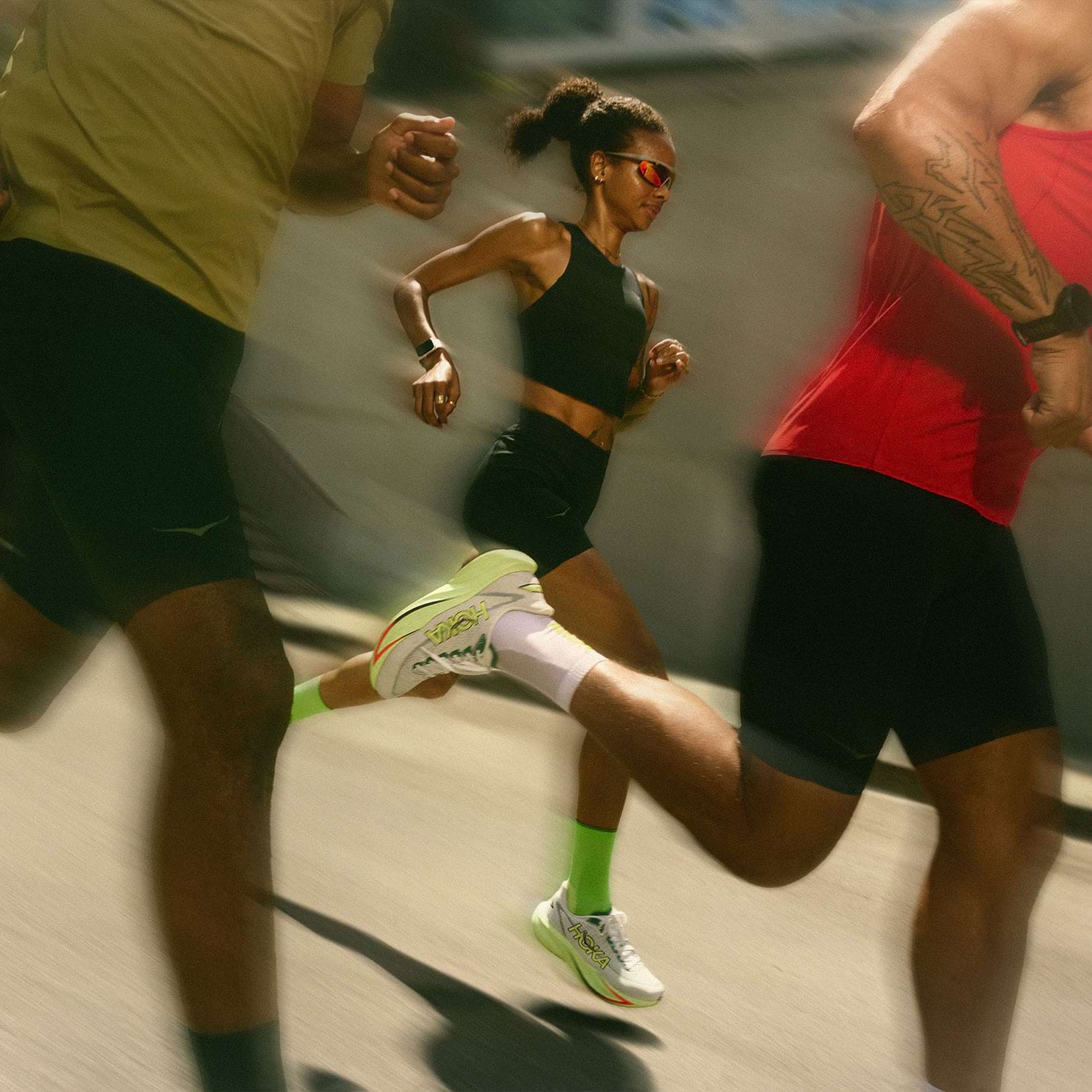 Three runners on a city street at night with a blurred, fast-moving background.