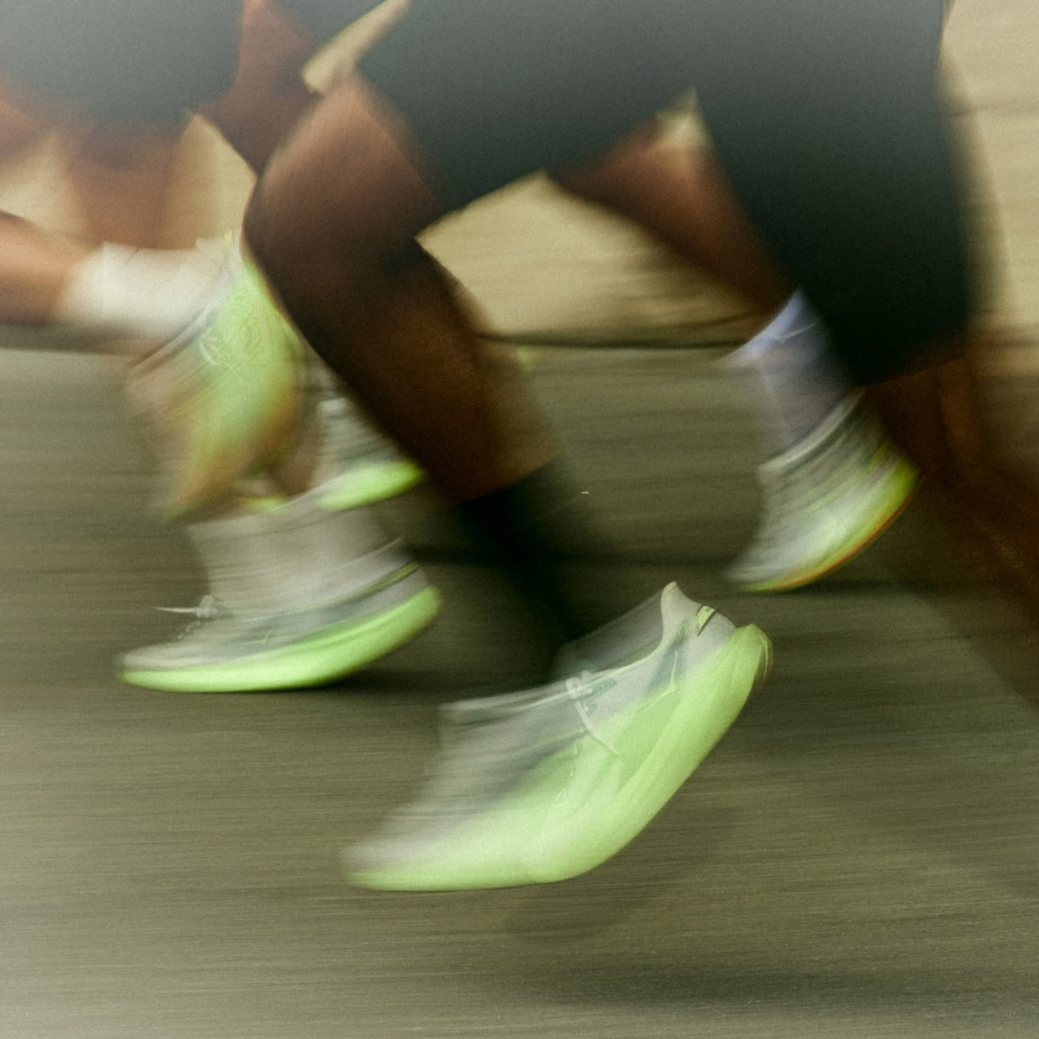 Three runners on a city street at night with a blurred, fast-moving background.