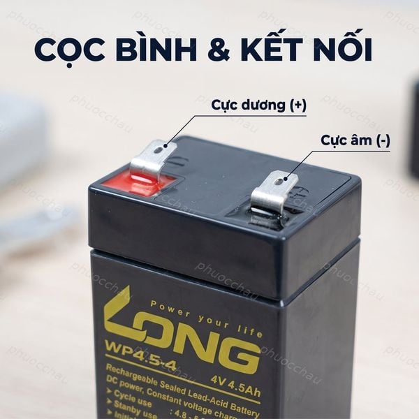 Bình ắc quy Long WP4.5-4 4V 4.5Ah cận cảnh cọc bình và kết nối: cực dương (+) bên trái có nắp đỏ, cực âm (-) bên phải, cọc dẹt có lỗ bắt vít