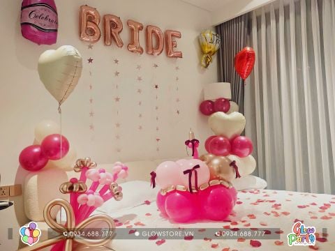 Không gian phòng cầu hôn được trang trí lãng mạn với tone màu hồng, bóng chữ Bride trên tường, giường rải cánh hoa hồng 