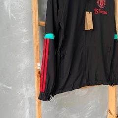 ÁO KHOÁC GIÓ MANCHESTER UNITED 2023/24 ĐEN PHỐI SỌC XANH NGỌC SỌC ĐỎ