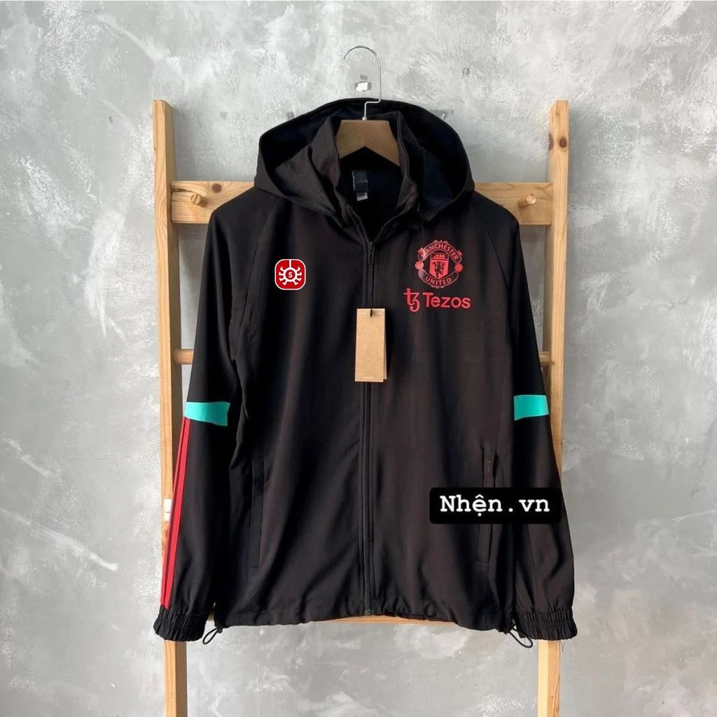 ÁO KHOÁC GIÓ MANCHESTER UNITED 2023/24 ĐEN PHỐI SỌC XANH NGỌC SỌC ĐỎ