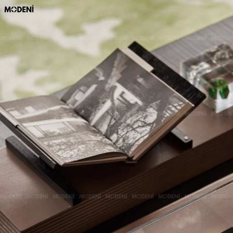 Góc chụp nghiêng trên mặt bàn làm việc, giá đỡ sách Novus nổi bật với màu gỗ đen nhám đang nâng đỡ một cuốn sách.
