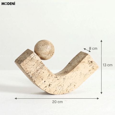 Góc chụp trực diện tượng trang trí cân bằng U-Sphere composite màu be đặt trên sách nghệ thuật.
