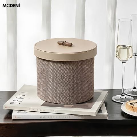 Hộp đựng mỹ phẩm Liora nắp da PU màu nâu be đặt trang nhã trên quyển tạp chí cạnh ly rượu vang.
