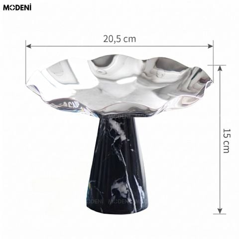 Góc chụp cận cảnh tô trái cây thép không gỉ lượn sóng đế đá cẩm thạch đen vân trắng đặt trên sách trang trí.