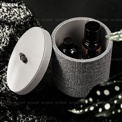 Tay người đang mở nắp hộp đựng mỹ phẩm Liora xám bọc vải nắp da khuy gỗ chống bụi, bên trong chứa chai lọ tinh dầu.