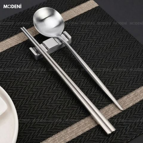 Đũa Riva Silver Inox 304 xước phay mờ màu bạc đặt trên dải khăn trải bàn họa tiết ziczac đen xám phản chiếu sang trọng.