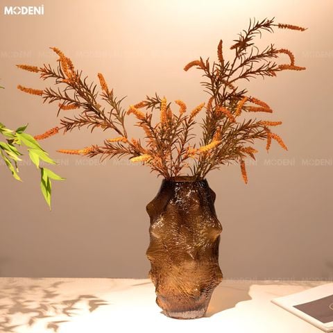 Hai bình hoa thủy tinh thủ công màu nâu hổ phách kích thước lớn nhỏ cắm cành hoa khô đặt trên khay gỗ.