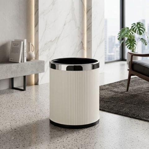 Thùng rác decor Vesta bọc da PU sọc dọc màu trắng be phối viền bạc chrome đặt trên thảm nỉ dệt xám cạnh sofa.