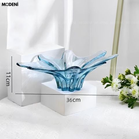 Góc chụp ngang tô trái cây thủy tinh lượn sóng màu xanh dương trong suốt đặt trên bục trưng bày trắng.