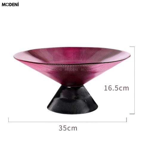 Góc chụp ngang tô trái cây thủy tinh sọc gân màu tím thạch anh đế kim loại đen đựng cam vàng.