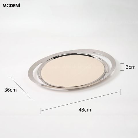 Khay trang trí Oval mặt da trắng be viền kim loại bạc đặt trên ghế đôn bọc lông cừu trắng cạnh cuốn tạp chí thời trang.