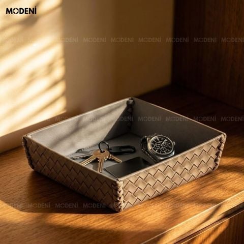 Góc chụp dưới ánh nắng trên bàn gỗ tròn khay trang trí nội thất phòng khách bọc da xám đựng nến thơm và thanh gỗ palo santo.