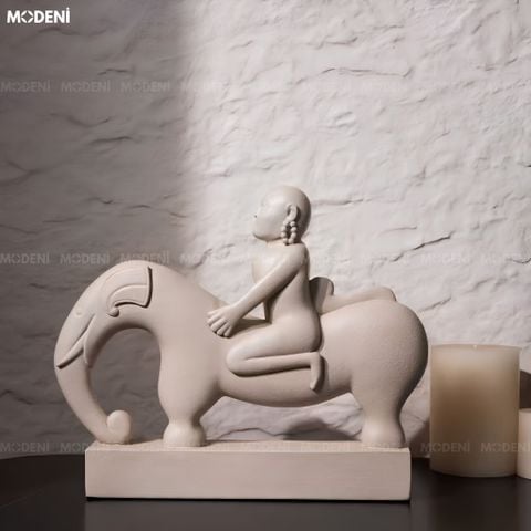 Góc nhìn chính diện tượng trang trí Nomad composite trừu tượng màu be đặt trên chồng sách nghệ thuật.