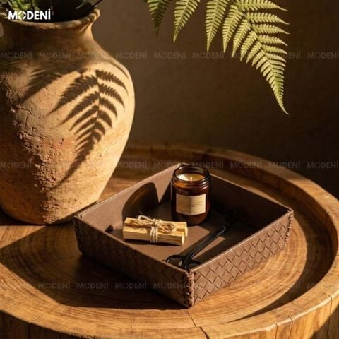 Góc chụp dưới nắng trên bàn gỗ tròn khay trang trí nội thất phòng khách bọc da nâu đậm đựng nến thơm và thanh gỗ palo santo.