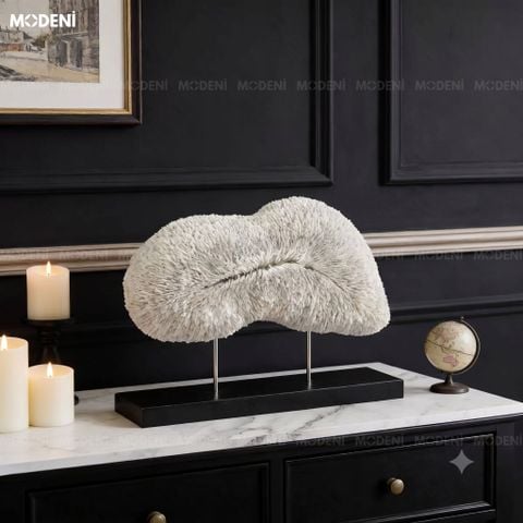 Góc chụp nghiêng trên bệ tủ đen, tượng trang trí Cumulus màu trắng nổi bật với vân san hô mềm mại cạnh nến mạ đồng.