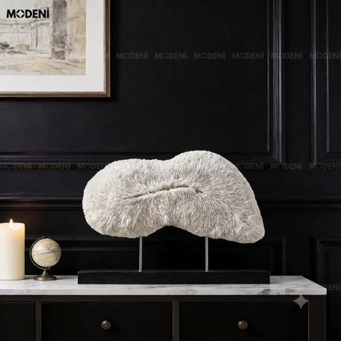 Góc chụp nghiêng trên bệ tủ đen, tượng trang trí Cumulus màu trắng nổi bật với vân san hô mềm mại cạnh nến mạ đồng.