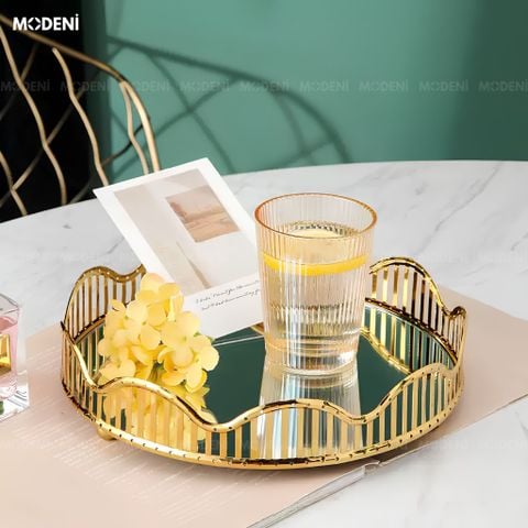 Góc chụp cận cảnh khay trang trí thủy tinh ánh kim viền vàng với thiết kế lượn sóng đang phản chiếu ánh sáng từ lọ nước hoa.