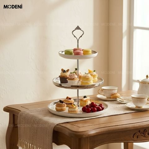 Khay tiệc trà thủy tinh chim vàng nhưng thực tế là khay 3 tầng sứ tráng men trắng bày biện bánh macaron, cupcake.