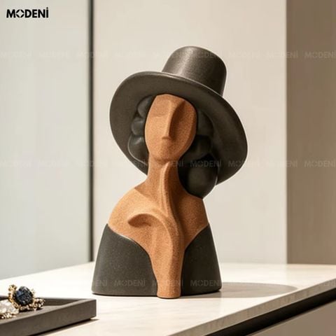 Trưng bày trên mặt bàn trắng, tượng trang trí Amelie hình cô gái đội mũ phối sắc nâu đất và đen nhám tinh tế.