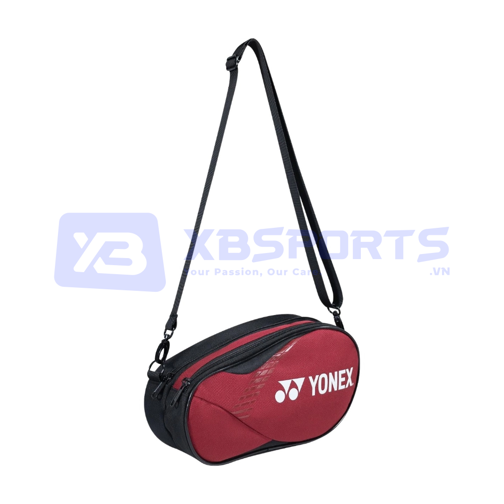 Túi đeo chéo dáng oval màu đỏ đô phối đen, khóa kéo chạy vòng quanh mặt túi, logo YONEX màu trắng in lớn, quai đeo dài màu đen có khóa điều chỉnh