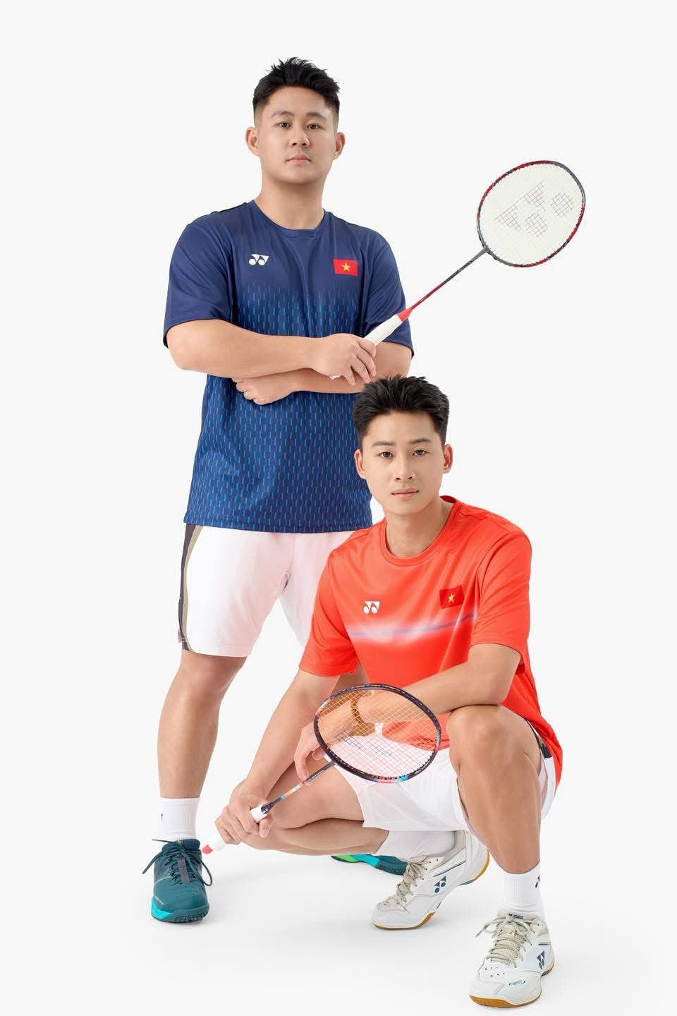Hai người mẫu mặc áo cầu lông Yonex Vietnam Open TRMYOB26147Z, một người mặc bản Dark Navy xanh đậm, một người mặc bản Cyber Orange đỏ cam, cả hai áo đều có logo YONEX trắng ở ngực trái và cờ đỏ sao vàng Việt Nam ở ngực phải, đều cầm vợt cầu lông