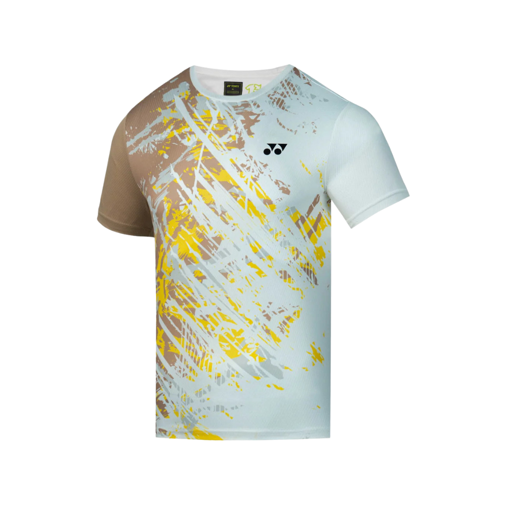 Áo cầu lông Yonex TRM2965 màu trắng, họa tiết vệt cọ màu vàng và nâu chạy chéo từ vai trái xuống thân trước, tay trái màu nâu be, logo Yonex màu đen ở ngực, cổ tròn