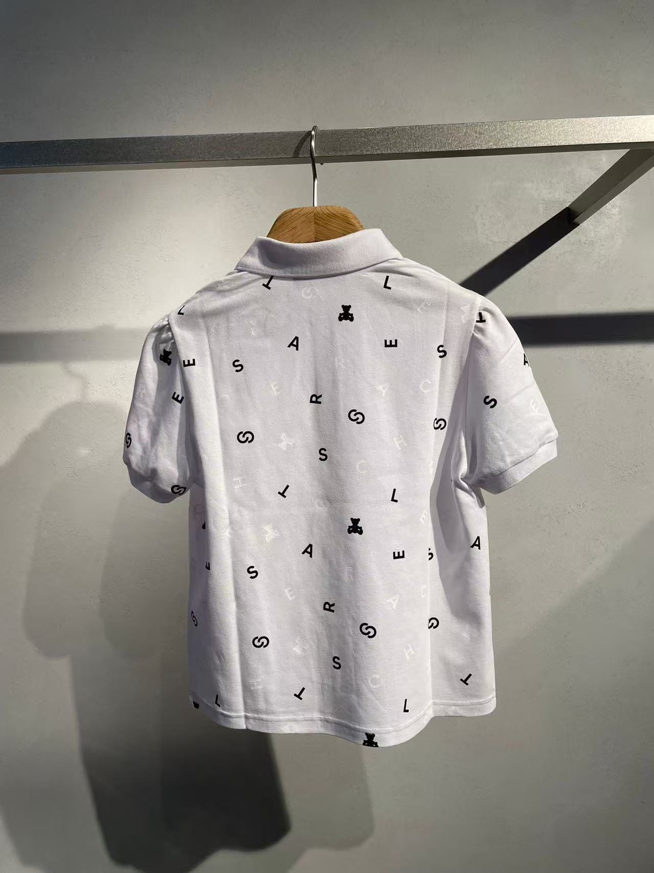  1.Áo polo trắng, họa tiết chữ, gấu đen 