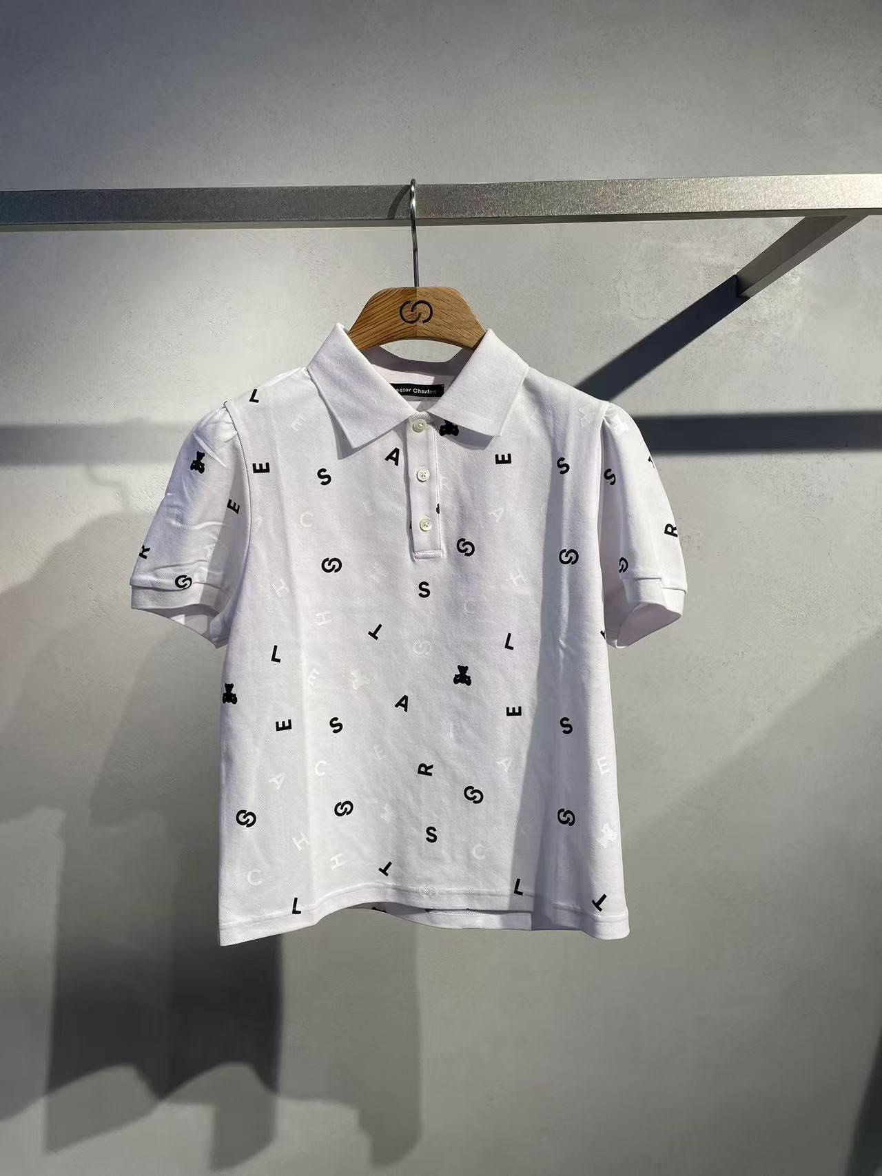  1.Áo polo trắng, họa tiết chữ, gấu đen 