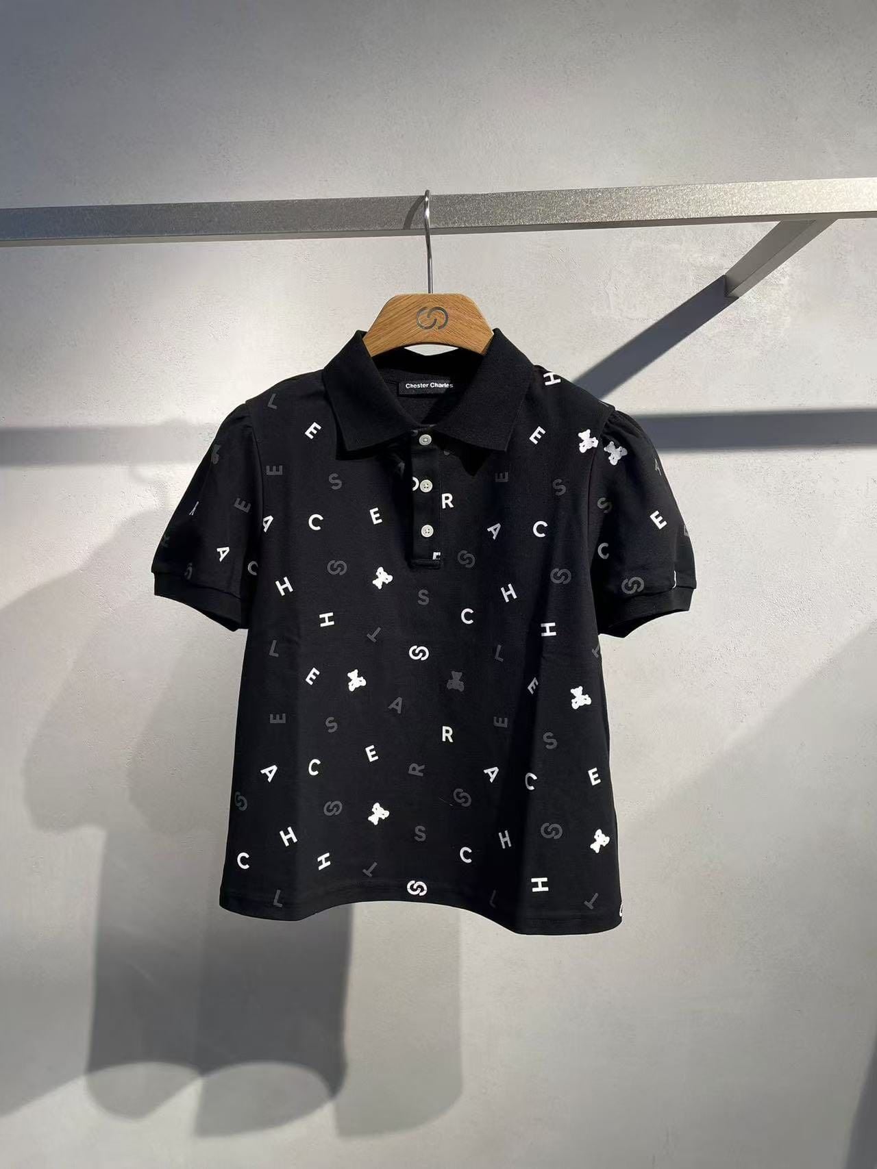  Áo polo đen, họa tiết chữ, gấu trắng 