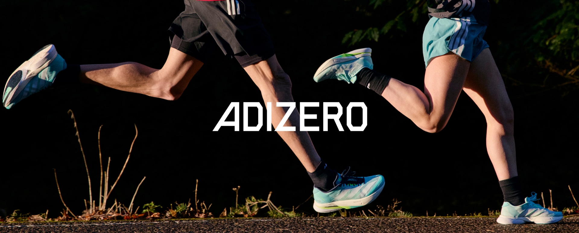 Cận cảnh đôi chân của vận động viên trên đường chạy lúc hoàng hôn, cả hai đều mang Adizero Boston 13 mới.
